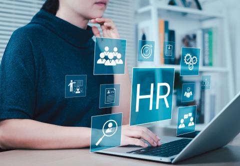 Manager works on laptop with HR icon showing to represent human resources