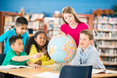 Diverse group of kids in a library using a globe