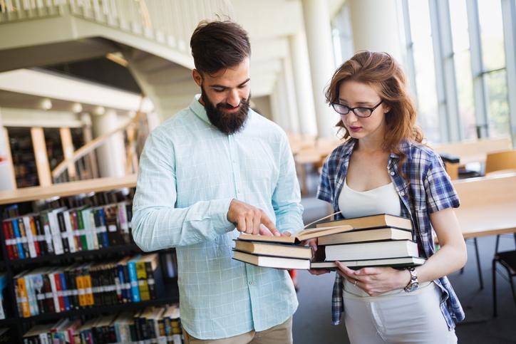 Two patrons looking at books in a library