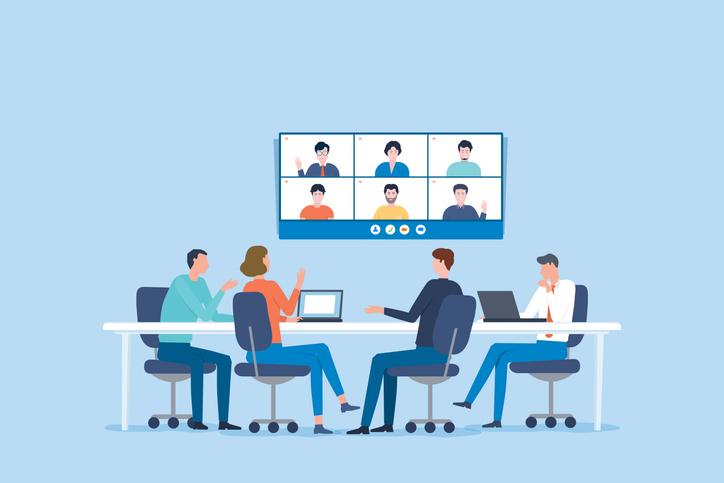Group of in-person and virtual meeting attendees networking.